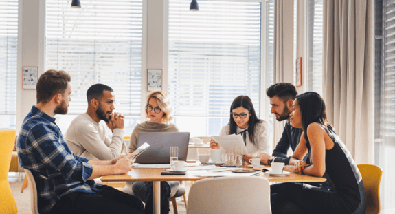 Hiring the Best Qualities of a Good EdTech Team - a group of people sit around a table working together-2